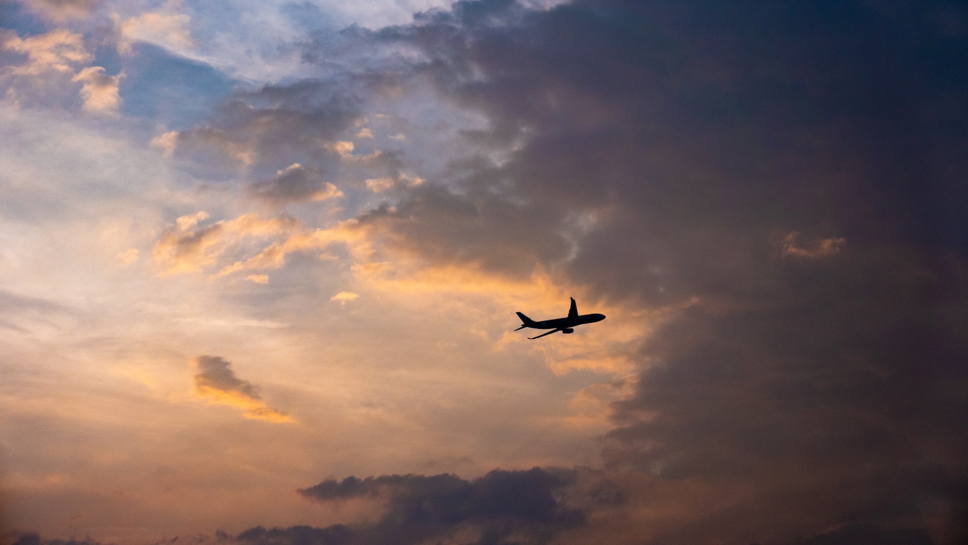 aeroplane flying through the sky with a sunset background