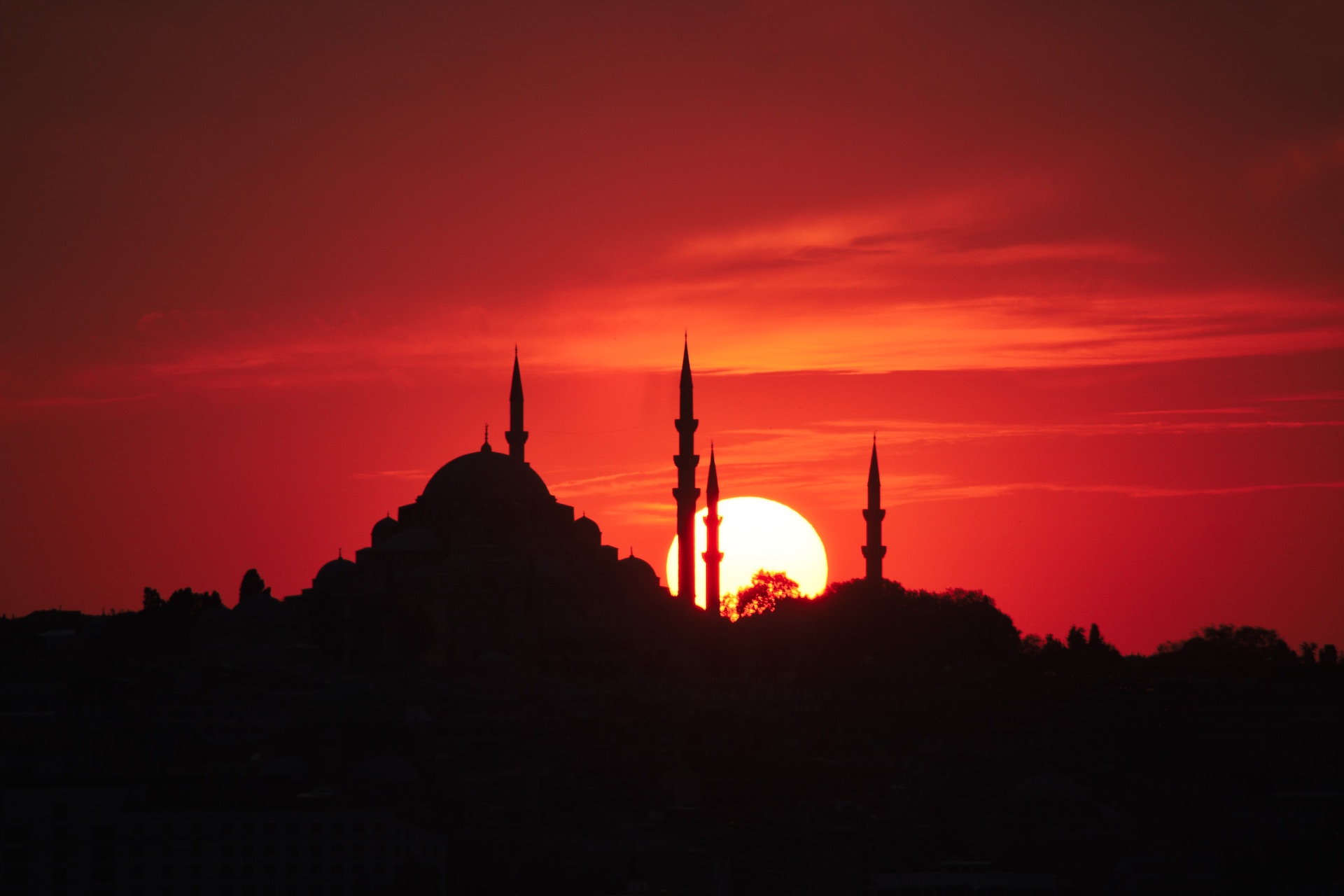 silhouette of mosque with red sky and sun in the background
